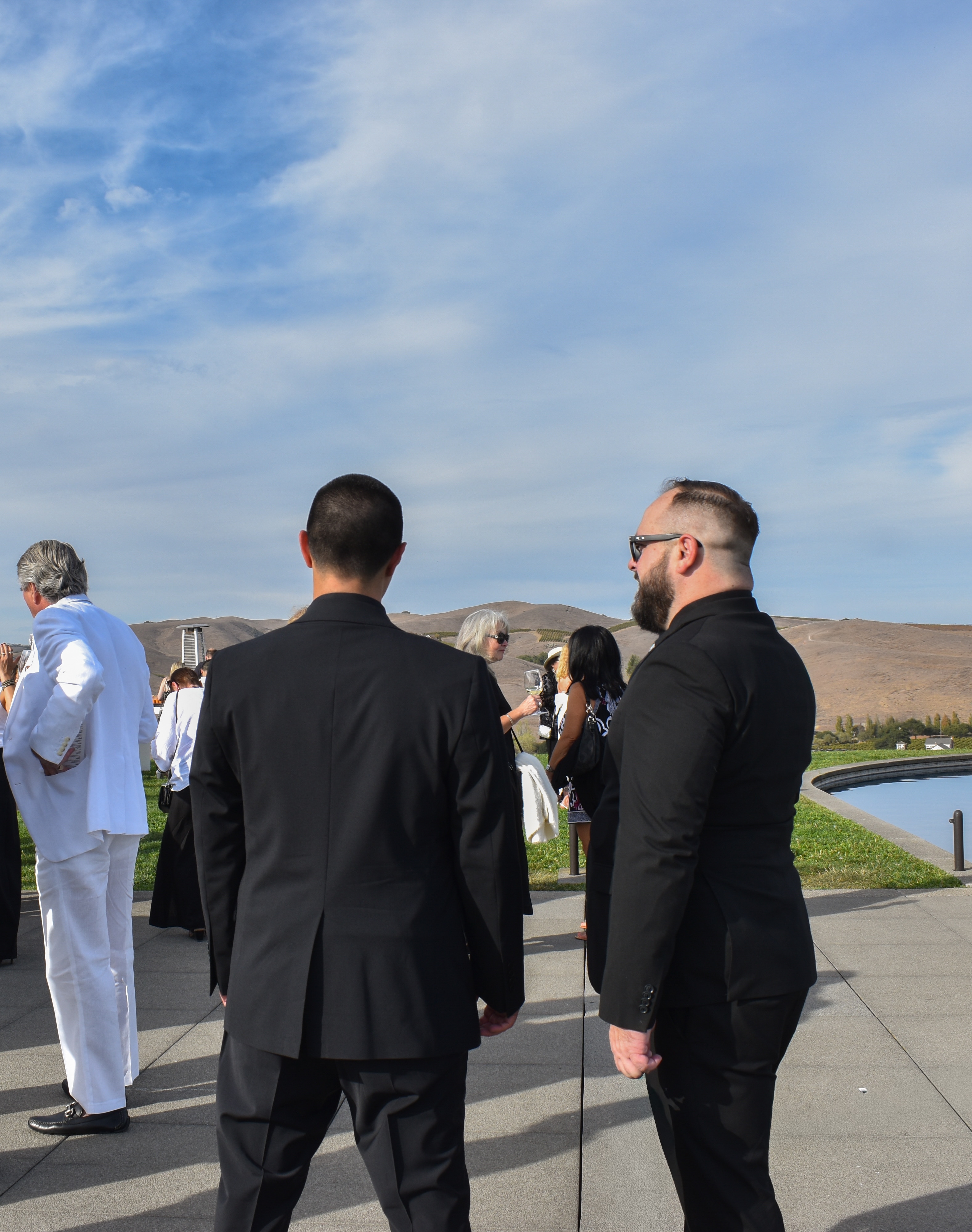 Agents in dark suits at an outdoor private event